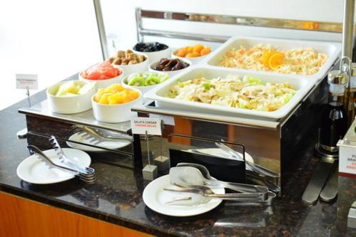 a buffet line with plates and bowls of food at Ramada Iasi City Center in Iaşi