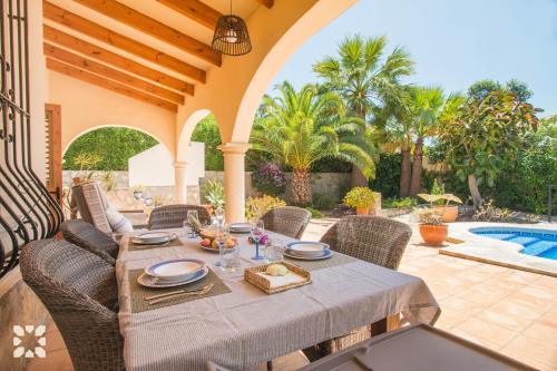 een patio met een tafel en stoelen en een zwembad bij Villa Ariane by Abahana Villas in Benitachell