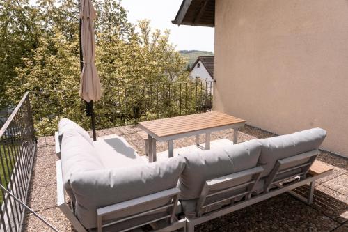 eine Terrasse mit einem Sofa, einem Tisch und einem Sonnenschirm in der Unterkunft TRIMOSA Apartments - cozy, modern und citynah in Trierweiler