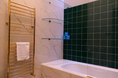 uma casa de banho com uma banheira e um chuveiro com azulejos verdes em Mamo Florence - Tintori Luxury Palace em Florença