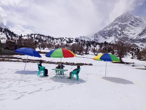 3 Personen sitzen an einem Tisch mit Sonnenschirmen im Schnee in der Unterkunft Summer Heaven Guesthouse in Tandal