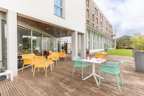 eine Terrasse mit Stühlen und Tischen auf einem Gebäude in der Unterkunft Appart’City Confort Nantes Ouest Saint-Herblain in Saint-Herblain