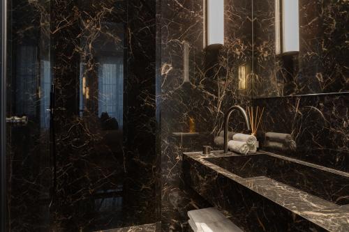 une salle de bain noire avec un lavabo et un miroir dans l'établissement TheLander - Serviced Apartments in Champs Elysées, à Paris