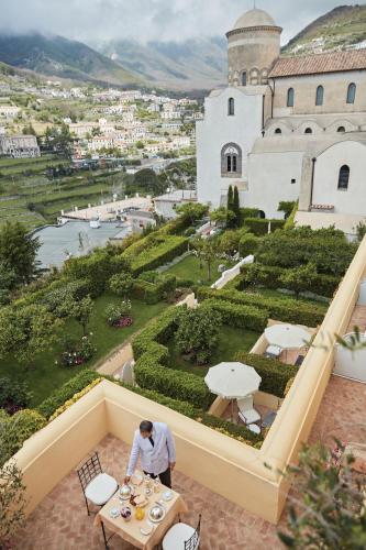 a man sitting at a table in front of a building at Caruso, A Belmond Hotel, Amalfi Coast in Ravello