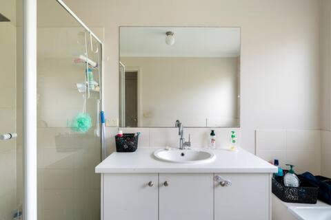 a bathroom with a sink and a shower with a mirror at Comfort Home in Wyndham Vale