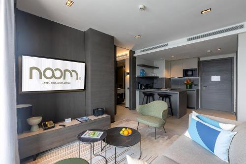 a living room with a couch and a tv on a wall at Noom Hotel Abidjan Plateau in Abidjan