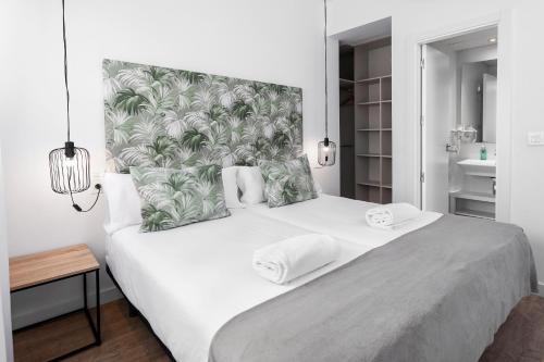a bedroom with a large white bed with a tropical headboard at Apartamentos de Isabella in Granada