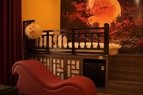 einen roten Stuhl in einem Raum mit einem Gemälde in der Unterkunft Tuyet Suong Hotel&LoveHouse in Đà Nẵng