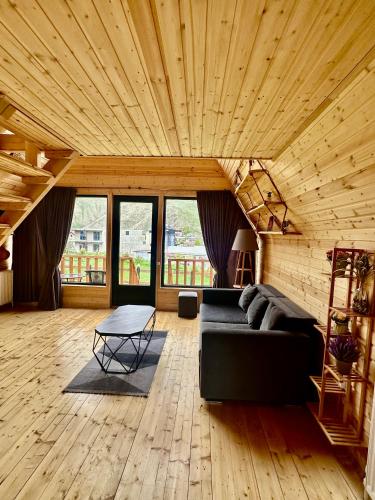 a living room with a black couch and wooden ceilings at Hillside Kazbegi in Stepantsminda