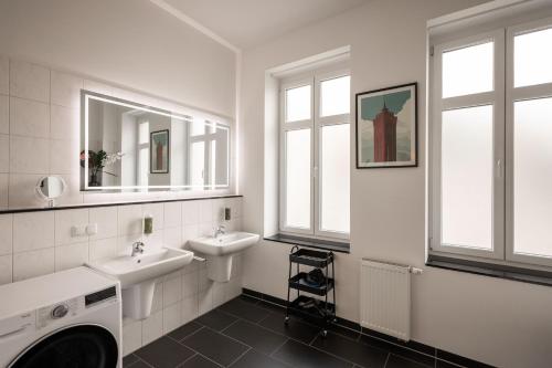 a white bathroom with two sinks and two mirrors at T21 - Boardinghouse im Citycenter mit Parkplatz in Chemnitz