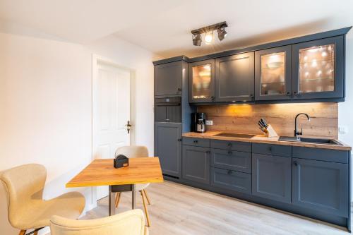 uma cozinha com armários azuis e uma mesa de madeira em Villa Albus App 7 em Ahlbeck