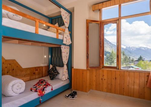 a bedroom with bunk beds with a window and mountains at Moustache Manali in Manāli