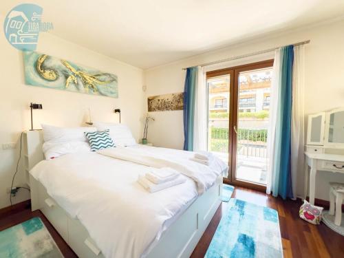 une chambre avec un grand lit blanc et une fenêtre dans l'établissement Porto San Rocco 12 Tirabora Short Rent, à Muggia