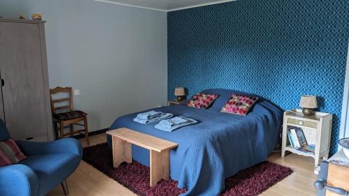 Schlafzimmer mit einem blauen Bett, einem Tisch und einem Stuhl in der Unterkunft chambre d'hôte la Sourdrie in Saint-Florent-le-Vieil