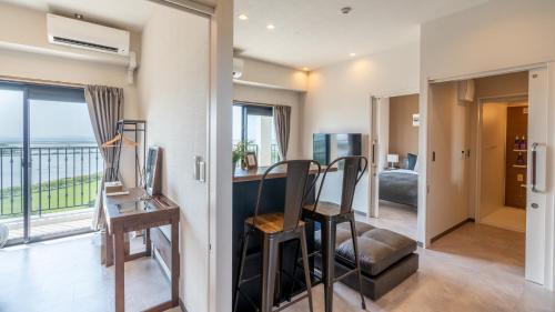 een woonkamer met een bureau en een balkon bij ホテルエアポートビューNAHA in Gushi