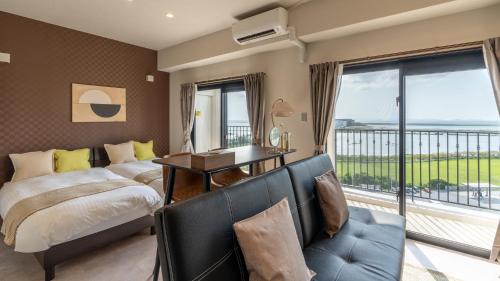 1 dormitorio con cama, escritorio y balcón en ホテルエアポートビューNAHA en Gushi