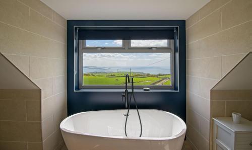 a bath tub in a bathroom with a window at High Auchenlarie Cottage in Gatehouse of Fleet