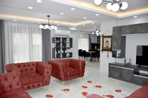 a living room with two red chairs and a television at gb’sluxuryhomes Antalya’daki eviniz in Belek