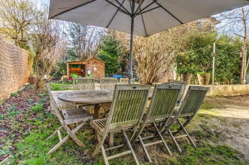 una mesa de madera con 4 sillas y una sombrilla en Large house with garden in Bougival - Welkeys, en Bougival