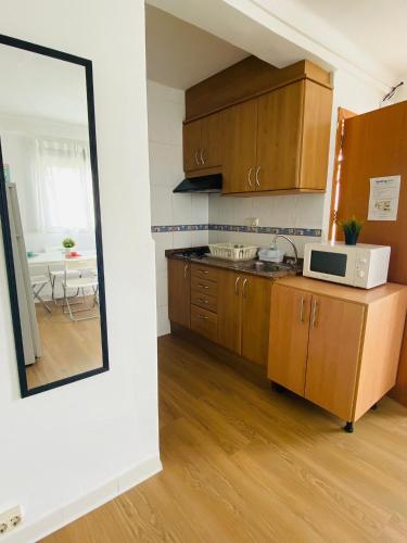 a kitchen with wooden cabinets and a microwave and a table at Apartamento Luna en Playa de Gandía in Gandía