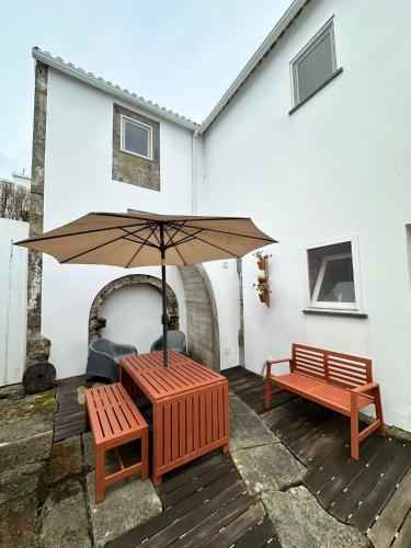 a patio with two benches and an umbrella at Apartamento acolhedor no centro da cidade, com pátio privado. in Angra do Heroísmo
