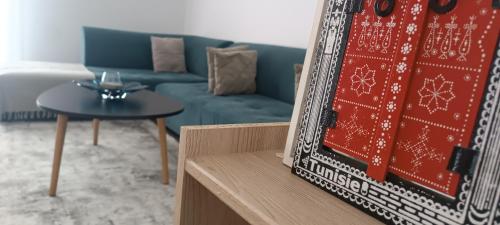 uma sala de estar com um sofá azul e uma mesa em Logement Chic, résidence azaléa - Alger em Draria