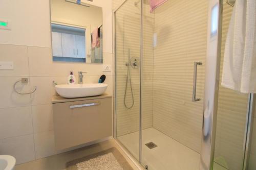 een badkamer met een glazen douche en een wastafel bij Condominio Meit in Lido di Jesolo