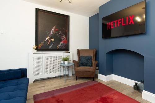 a living room with a couch and a tv on a wall at Stratford House in Braunstone