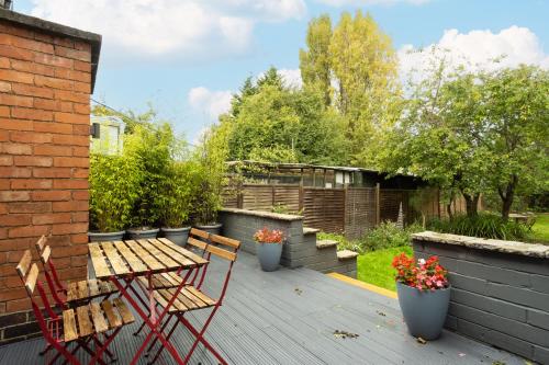 eine Terrasse mit einem Holztisch, Stühlen und Pflanzen in der Unterkunft Stratford House in Braunstone