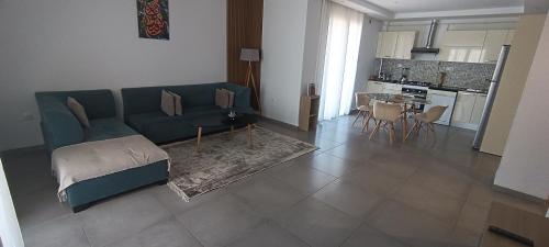 Logement Chic, résidence azaléa - Alger في Draria: غرفة معيشة مع أريكة زرقاء ومطبخ