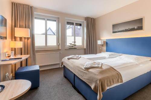 a bedroom with a large bed and a table at Nordsee-Hotel Hinrichsen in Husum