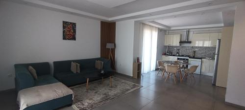 a living room with a couch and a table and a kitchen at Logement Chic, résidence azaléa - Alger in Draria