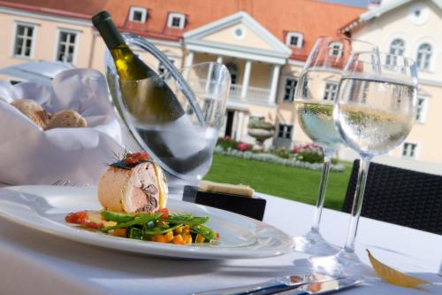 a table with a plate of food and two glasses of wine at Vihula Manor Country Club & Spa in Vihula