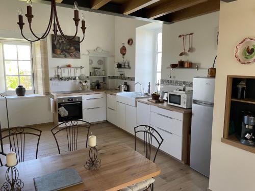 une cuisine avec des armoires blanches et une table et des chaises dans l'établissement LE MAYNE, à Puisseguin