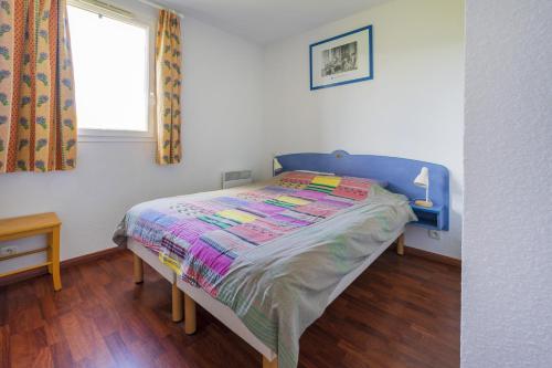 Gîte Le coeur des Landes في Cassen: غرفة نوم مع سرير مع اللوح الأمامي الأزرق ونافذة