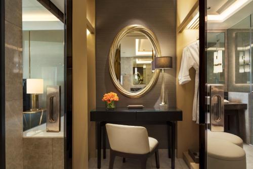 a bathroom with a vanity and a mirror and a chair at Siam Kempinski Hotel Bangkok in Bangkok
