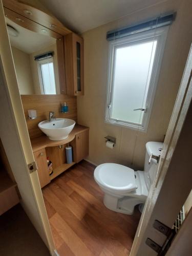 uma casa de banho com um WC, um lavatório e uma janela em Seaside caravan Hoburne Naish Holiday Park Naish Common 83 em New Milton