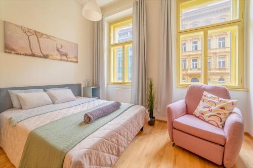 een slaapkamer met een bed en een stoel en 2 ramen bij Historic City Center Deer Suite by Rentez in Praag