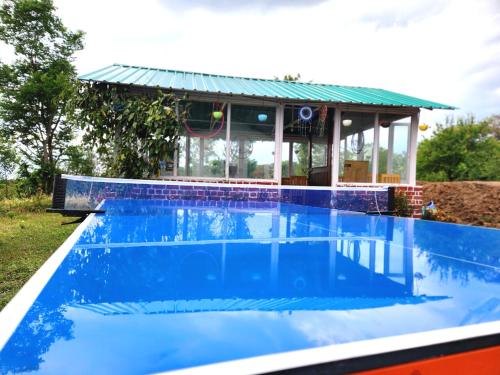a blue swimming pool with a building in the background at Hipostel Bir - Stay and Cafe in Bīr