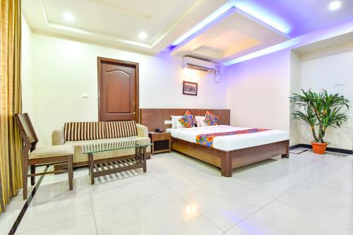 een slaapkamer met een bed, een bank en een stoel bij FabHotel Shakti Palace in Ponda