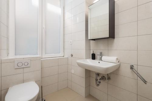 a white bathroom with a toilet and a sink at Molo Longo - Downtown Apartments in Rijeka