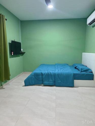 Cette chambre comprend un lit bleu et une télévision. dans l'établissement D cateleya homestay, à Beranang