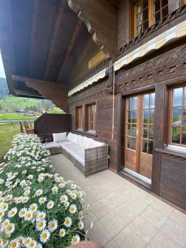 a patio with a white couch and some flowers at Lovely 3 bedroom apartment in Schönried