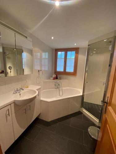 a bathroom with a tub and a sink and a shower at Lovely 3 bedroom apartment in Schönried