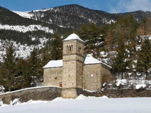 a brick building in the snow with mountains in the background at Apartamentos Casa Boira 3000 in Gavín