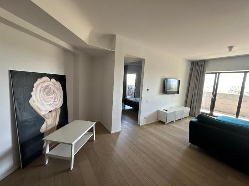 ein Wohnzimmer mit einem Sofa und einem Rosengemälde in der Unterkunft Apartament lux cotroceni in Bukarest