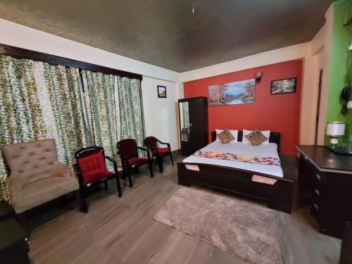 1 dormitorio con 1 cama y sillas en una habitación en Stay Inn Eastwood Guest House, en Shillong