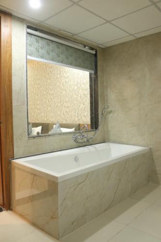 a bath tub in a bathroom with a mirror at Hotel maxsun gwalior in Gwalior