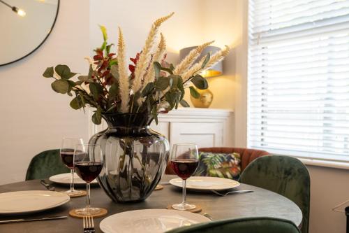 a table with glasses of wine and a vase with flowers at Stapenhill House in Burton upon Trent