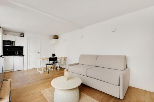 un salon avec un canapé blanc et une table dans l'établissement Pick A Flat's Apartment in Louvre - Rue Saint-Anne, à Paris